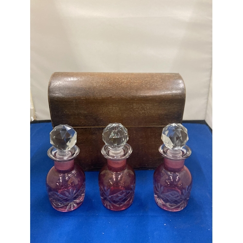 2 - A VINTAGE LINED WOODEN CHEST WITH THREE CRANBERRY GLASS BOTTLES COMPLETE WITH KEY