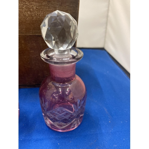 2 - A VINTAGE LINED WOODEN CHEST WITH THREE CRANBERRY GLASS BOTTLES COMPLETE WITH KEY