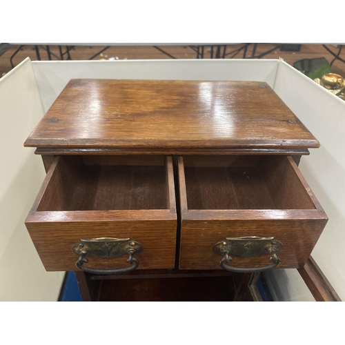 42 - A VINTAGE OAK SMOKERS CABINET WITH TWO SHORT UPPER DRAWERS, A GLAZED DOOR AND A LONG LOWER DRAWER AN... 