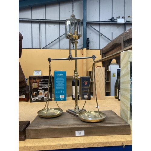 62 - A SET OF BRASS BALANCE SCALES ON A WOODEN BASE