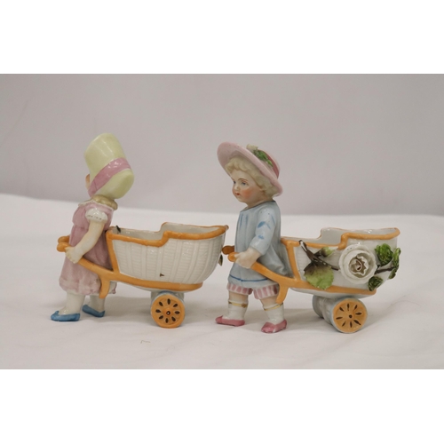 963 - TWO VINTAGE CONTA AND BOHME GERMAN FAIRINGS TO INCLUDE TWO GIRLS PULLING FLOWER CARTS, ONE WITH A HA... 