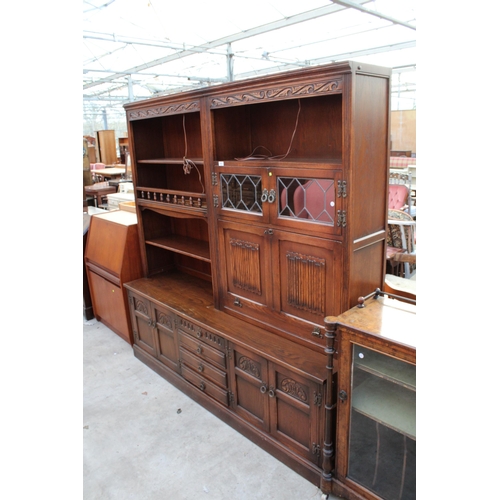 2557 - AN OAK OLD CHARM LOUNGE UNTI WITH GLAZED AND LEADED LINEN FOLD DOORS WITH CUPBOARDS AND DRAWERS TO T... 