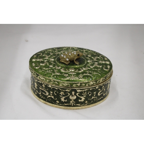 110 - A GREEN ENAMELLED KEEPSAKE/JEWELLERY BOX WITH A JEWELLED FRONG ON THE LID, HEIGHT 8CM, DIAMETER, 16C... 