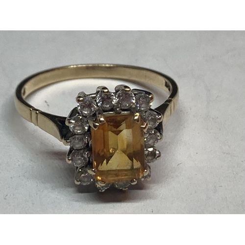 506 - A 9 CARAT GOLD RING WITH A CENTRE CITRINE SURROUNDED BY CUBIC ZIRCONIAS SIZE R