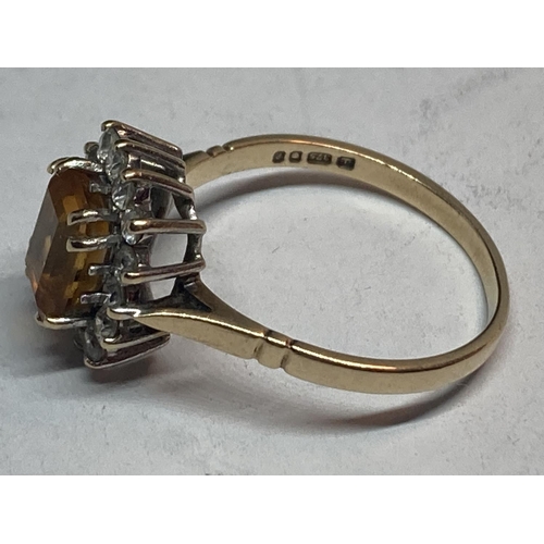 506 - A 9 CARAT GOLD RING WITH A CENTRE CITRINE SURROUNDED BY CUBIC ZIRCONIAS SIZE R