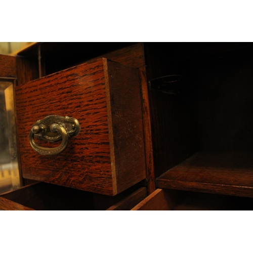 52 - AN OAK TWO GLASS DOOR SMOKERS CABINET WITH THREE INTERIOR DRAWERS ONE LABELED PLAYING CARDS COMPLETE... 