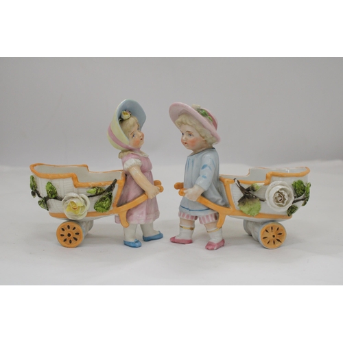 236 - TWO VINTAGE CONTA AND BOHME GERMAN FAIRINGS TO INCLUDE TWO GIRLS PULLING FLOWER CARTS, ONE WITH A HA... 