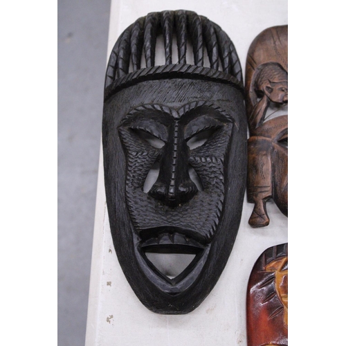 132 - FIVE AFRICAN HAND CARVED WOODEN MASKS - PLUS TWO SPEARS