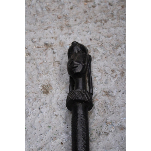 170 - AN ETHNIC AFRICAN BLACK WOODEN SPEAR - WITH CARVED HEAD DECORATION TO THE TOP