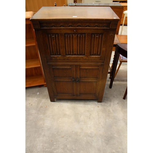 2555 - AN OAK CHARM STYLE COCKTAIL CABINET WITH LINEN-FOLD DROP DOWN FRONT AND CUPBOARD TO BASE, 31.5