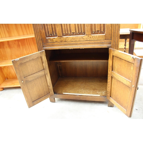 2555 - AN OAK CHARM STYLE COCKTAIL CABINET WITH LINEN-FOLD DROP DOWN FRONT AND CUPBOARD TO BASE, 31.5