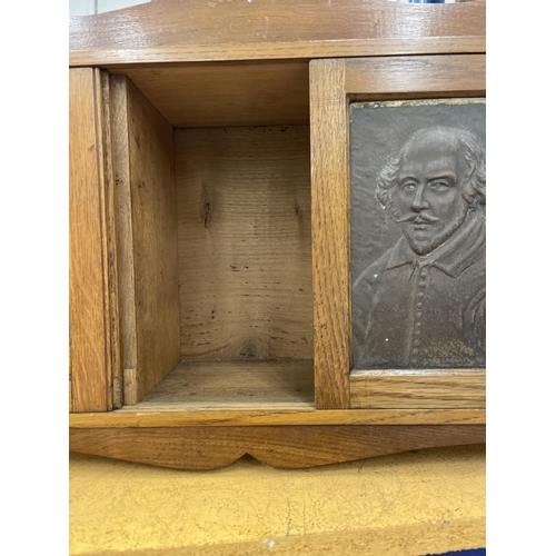 74 - AN EDWARDIAN OAK SMOKERS CABINET DEPICTING WILLIAM SHAKESPEARE WITH THREE SECTIONS. RIGHT HAND DOOR ... 