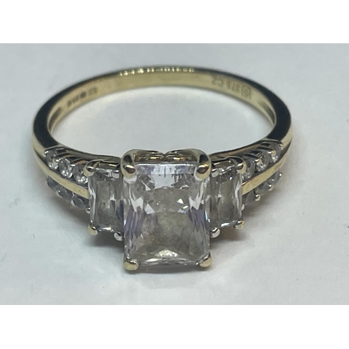 658 - A 9 CARAT GOLD RING WITH A LARGE CENTRE CUBIC ZIRCONIA AND SMALLER TO THE SHOULDERS SIZE O