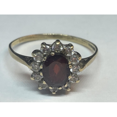 659 - A 9 CARAT GOLD RING WITH A CENTRE GARNET SURROUNDED BY CUBIC ZIRCONIAS SIZE V