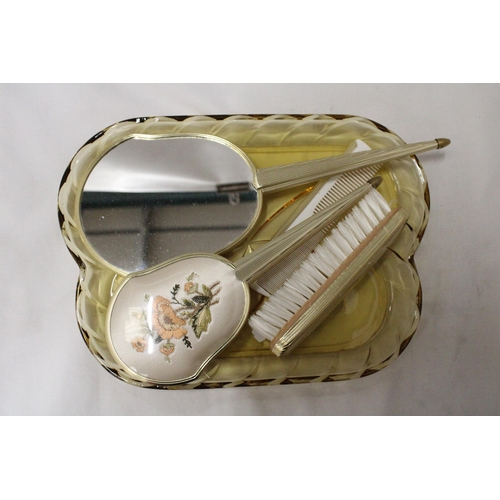 285 - A VINTAGE DRESSING TABLE BRUSH TO INCLUDE, GLAS TRAY, TWO BRUSHES, A MIRROR AND COMB, WITH EMBROIDER... 