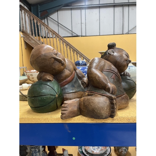 70 - TWO LARGE CARVED HARDWOOD ORIENTAL FIGURES OF A SLEEPING BOY AND GIRL APPROXIMATELY 22CM TALL