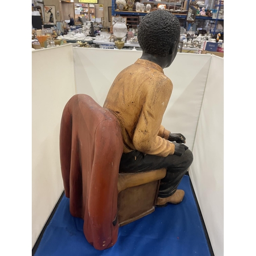 76 - A LARG FIGURE OF A MAN SITTING IN A CHAIR