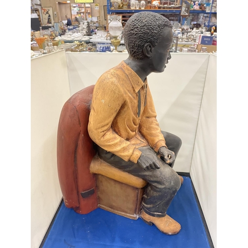 76 - A LARG FIGURE OF A MAN SITTING IN A CHAIR