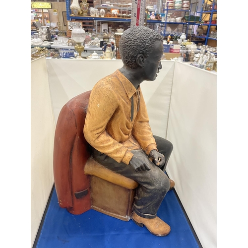 76 - A LARG FIGURE OF A MAN SITTING IN A CHAIR