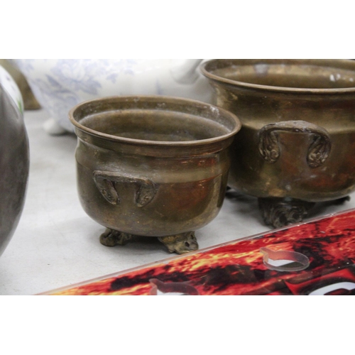 216 - THREE GRADUATED BRASS FOOTED AND HANDLED POTS