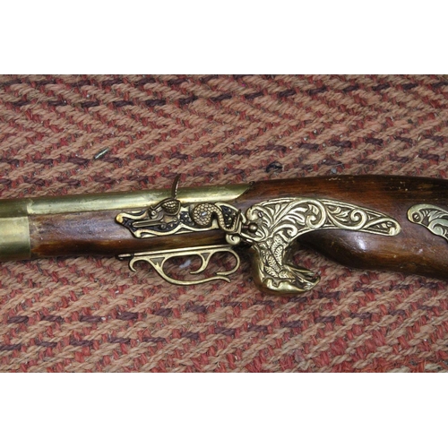 1075 - A HEAVY HARDWOOD AND BRASS WALL MOUNTED RIFLE -APPROXIMATELY 104CM