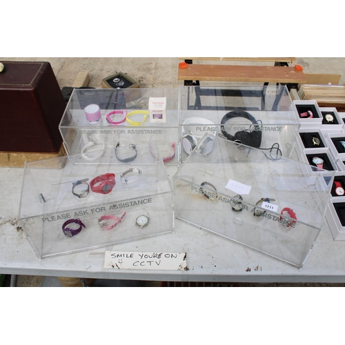 1711 - FOUR PLASTIC DISPLAY STANDS WITH AN ASSORTMENT OF FASHION WATCHES AND HEADPHONES