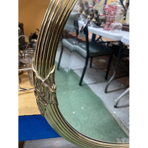 66 - A LARGE GILT FRAMED OVAL WALL MIRROR WITH A DECORATIVE RIBBON DESIGN FRAME