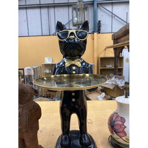 86 - A DUMB WAITER IN THE FORM OF A BLACK BULLDOG WEARING GOLD COLOURED SUNGLASSES AND HOLDING A MATCHING... 