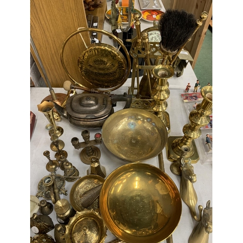 1007 - A LARGE QUANTITY OF BRASSWARE TO INCLUDE A GONG WITH STRIKER, COMPANION SET, BOWLS, CANDLESTICKS, HO... 