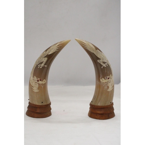 296 - A PAIR OF REAL ORIENTAL HORNS ON WOOD BASES WITH DRAGON DESIGN, HEIGHT 23CM