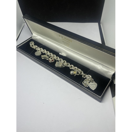 579 - A TIFFANY & CO SILVER CHARM BRACELET WITH SIX CHARMS IN A PRESENTATION BOX