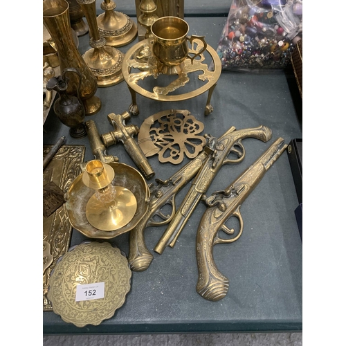 152 - A LARGE COLLECTION OF BRASSWARE TO INCLUDE CANDLESTICKS, WALL HANGING GUNS, A TRIVET, PLATESS, WALL ... 