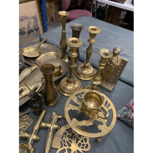152 - A LARGE COLLECTION OF BRASSWARE TO INCLUDE CANDLESTICKS, WALL HANGING GUNS, A TRIVET, PLATESS, WALL ... 