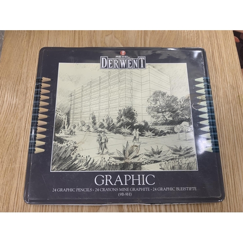 164 - AN ART BOX AND EASEL WITH BRUSHES, PAPER AND A TIN OF FOURTEEN, DERWENT GRAPHIC PENCILS