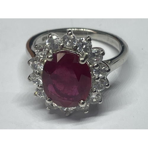 546 - A MARKED 925 SILVER RING WITH CENTRE RUBY COLOURED STONE SURROUNDED BY CLEAR SONES SIZE R IN A PRESE... 