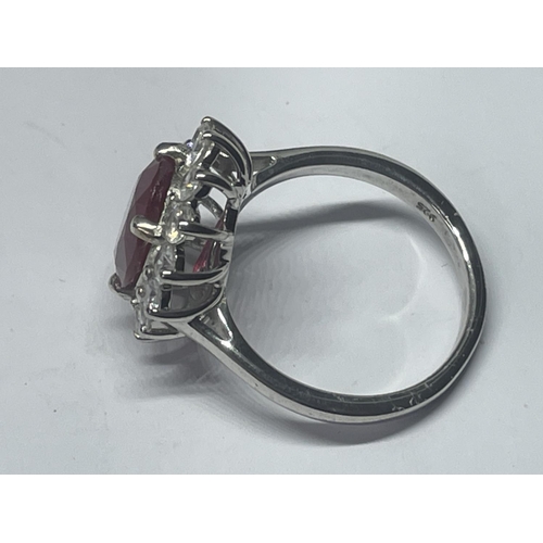 546 - A MARKED 925 SILVER RING WITH CENTRE RUBY COLOURED STONE SURROUNDED BY CLEAR SONES SIZE R IN A PRESE... 