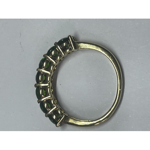 553 - A MARKED 925 SILVER GILT RING WITH SEVEN IN LINE EMERALD COLOURED STONES SIZE L/M IN A PRESENTATION ... 