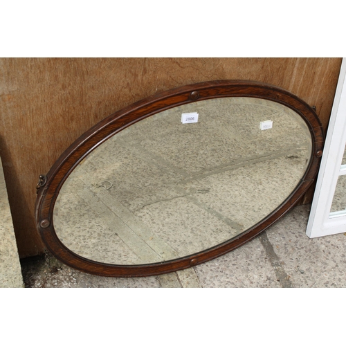 2806 - AN EARLY 20TH CENTURY OVAL OAK BEVEL EDGED WALL MIRROR