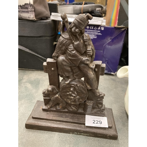 229 - A HEAVY CAST BAG-PIPER AND DOG DOORSTOP ON PEDESTAL