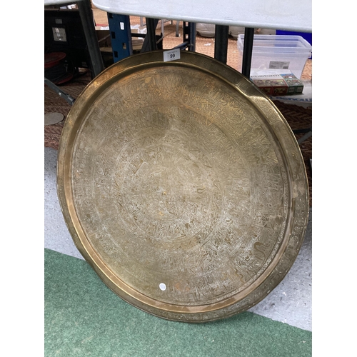 99 - A LARGE BRASS CHARGER WITH INTRICATE EGYPTIAN DESIGN - 64 CM DIAMETER