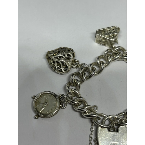 748 - A VINTAGE SILVER CHARM BRACELET WITH SEVEN CHARMS