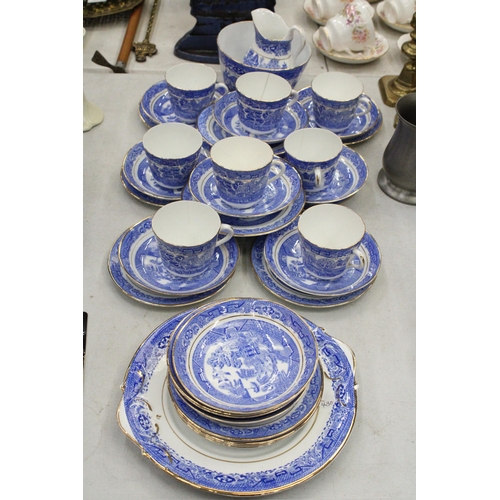 174 - A QUANTITY OF ANTIQUE BLUE WILLOW WITH GOLD TRIM TO INCLUDE SLOP BOWL, MILK JUG, CUPS, SAUCERS, SIDE... 