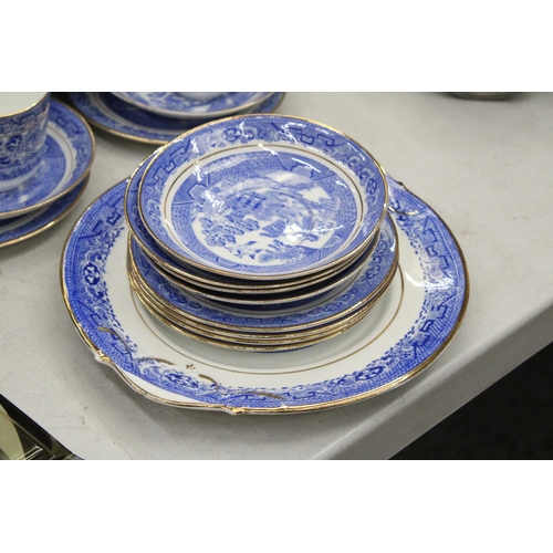 174 - A QUANTITY OF ANTIQUE BLUE WILLOW WITH GOLD TRIM TO INCLUDE SLOP BOWL, MILK JUG, CUPS, SAUCERS, SIDE... 