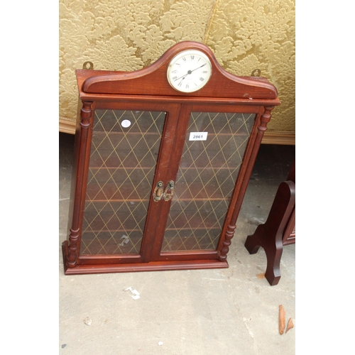 2861 - A TWO DOOR WALL DISPLAY CASE SURMOUNTED WITH A QUARTZ CLOCK