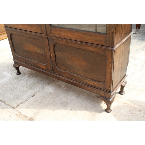 3006 - AN EARLY 20TH CENTURY OAK BOOKCASE WITH TWO GLAZED AND LEADED DOORS AND PANELLED DOORS TO BASE ON CA... 