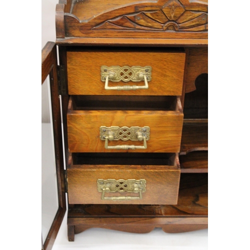 38 - A VINTAGE OAK WOOD SMOKERS CABINET WITH DOUBLE BEVELLED GLASS DOORS AND DECORATIVE BRASS HANDLES