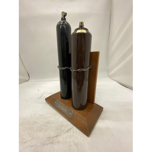 16 - TWO MINIATURE GAS CYLINDERS ON A WOODEN STAND PRESENTED BY ALL AT B.O.C. AS A RETIREMENT GIFT