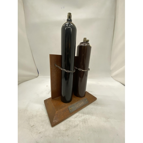 16 - TWO MINIATURE GAS CYLINDERS ON A WOODEN STAND PRESENTED BY ALL AT B.O.C. AS A RETIREMENT GIFT