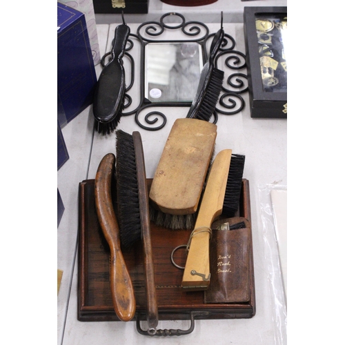 294 - A VINTAGE WROUGHT IRON FRAMED MIRROR WITH SHOE SHINE GROOMING BRUSHES TOGETHER WITH FURTHER BRUSHES,... 