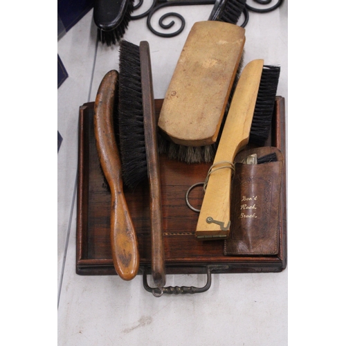 294 - A VINTAGE WROUGHT IRON FRAMED MIRROR WITH SHOE SHINE GROOMING BRUSHES TOGETHER WITH FURTHER BRUSHES,... 